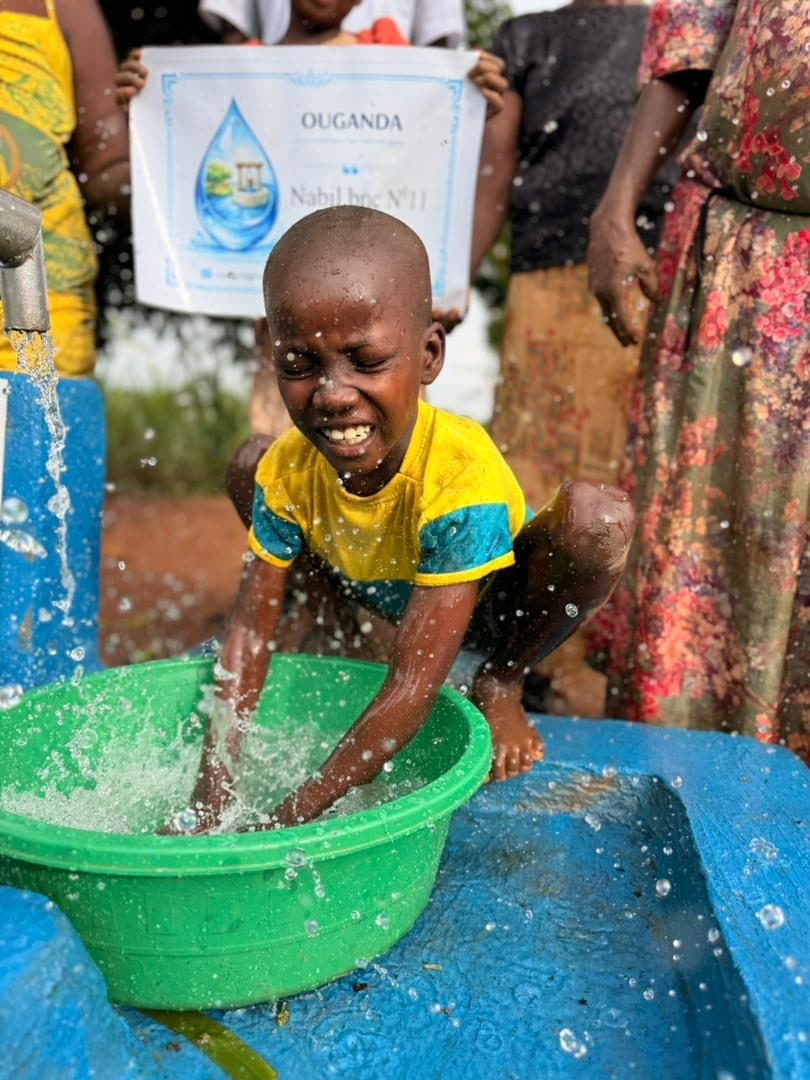 Un enfant rit sous l'eau qui remplit une bassine