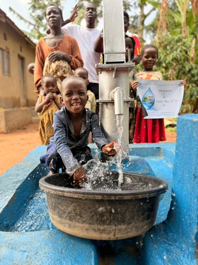 A child drinks from the water running out of the pump